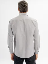 Camisa de corte regular confeccionada en tejido oxford, color azul claro. Presenta cuello con botones, cierre frontal abotonado, mangas largas con puños y un bolsillo frontal en el pecho.