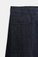 Pantalón de jean azul oscuro de tiro medio, con corte holgado y diseño de pierna ancha. Presenta cintura elástica en la parte posterior, cierre frontal con cremallera y botón metálico, y bolsillos de plastrón en el delantero.