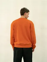 Buzo básico de felpa color naranja, con cuello redondo y logo de Umbro bordado en el pecho.