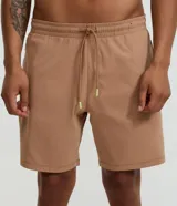 Bermuda deportiva color beige, confeccionada en poliéster, con cintura elástica y cordón de ajuste. Presenta bolsillos laterales y costuras contrastantes.