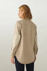 Camisa estilo leñador color beige con textura en espiga, de manga larga, con cuello clásico, cierre frontal con botones, dos bolsillos de parche con solapa abotonada en el pecho y puños abotonados. Confeccionada en lana fina sin teñir.