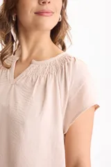 Blusa negra de manga corta, confeccionada en tela crepé, con detalle de fruncido en el escote redondo y pequeña abertura frontal en V.