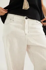 Pantalón de corte recto y tiro medio con costuras a la vista, bolsillos delanteros y traseros, y un detalle de pin de la marca en el ruedo.