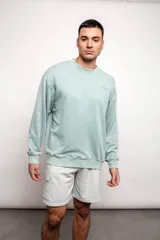 Buzo verde agua liso, de corte oversize, confeccionado con 60% algodón y 40% poliéster.