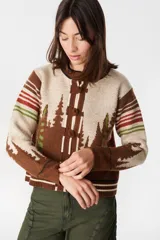 Cardigan de lana con diseño estampado de bosque de pinos en tonos marrones, verdes y crudo. Presenta cuello redondo, cierre frontal con botones forrados y puños acanalados.