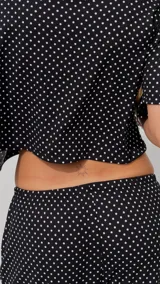 Pantalón negro de algodón y viscosa, con estampado de lunares blancos y corte holgado.