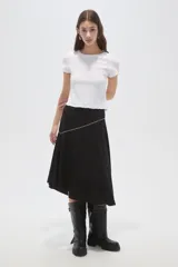 Falda midi negra de corte asimétrico, con detalle de costura diagonal decorada con pequeñas tachas metálicas.