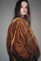 Kimono abierto de terciopelo color marrón, con diseño acolchado y bordados florales en hilo dorado en el frente. Presenta mangas largas y costuras decorativas a contraste.
