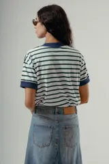 Camiseta de algodón orgánico con diseño a rayas horizontales verdes y blancas, cuello redondo y bordes de mangas en color azul marino. Presenta una letra R bordada en el pecho.
