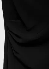 Vestido midi de color negro, sin mangas, con cuello redondo y diseño entallado. Presenta un detalle de fruncido lateral y cierre de cremallera en la parte posterior.