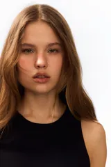 Vestido corto negro sin mangas, con escote redondo, cuerpo entallado y falda acampanada con frunces caídos en la cadera.