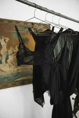 Bata corta de seda negra, con mangas anchas terminadas en encaje. Se ajusta a la cintura con un lazo del mismo material.