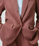 Blazer de sastrería color marrón, de modelaje comfort, corte estructurado y largo medio. Cuenta con cuello con solapa, cierre frontal de botón único, bolsillos con tapa y mangas largas.