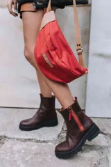 Botas de cuero marrón con suela track de goma negra, cierre lateral en color rojo y detalle de tira trasera al tono.