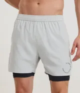 Bermuda deportiva verde militar con short de compresión incorporado, cintura elástica y cordón ajustable, confeccionada en microfibra de poliéster y elastano.