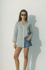 Camisa de lino 100% con rayas verticales blancas y negras, de calce relajado, cuello camisero y mangas largas.