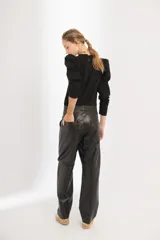 Pantalón de cuero negro de tiro medio, con fit oversized y piernas estilo slouchy, bolsillos laterales y cierre frontal.