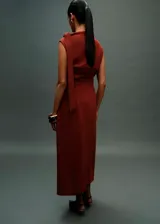 Vestido midi de fiesta color terracota, con cuello barco y diseño sin mangas. Presenta detalles fruncidos en la cintura y un detalle de nudo en el hombro, con un corte entallado y cierre posterior.