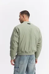 Campera tipo bomber de nylon color verde oliva, con cierre frontal, cuello, puños y cintura elastizados.