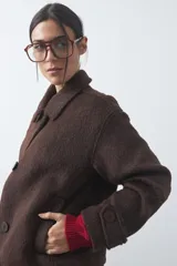 Tapado corto de paño con textura, color marrón, de corte recto y silueta estructurada. Presenta cuello camisero, cierre frontal con botones grandes y mangas largas con detalle de trabas en los puños.