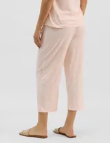 Pijama compuesto por remera sin mangas con escote redondo, botones frontales y detalle de puntilla, acompañado de un pantalón capri con cintura elástica. Presenta un estampado floral en tonos rosados sobre base gris.