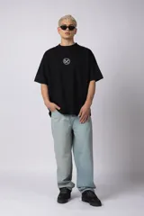 Remera oversize de algodón negro, con cuello redondo y manga corta ancha. Presenta un pequeño logo bordado en el pecho con un símbolo de prohibido fumar.