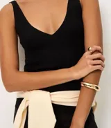 Blusa sin mangas de punto acanalado color crema, con escote en V y espalda descubierta. Confeccionada en una mezcla de viscosa y poliamida, presenta un ajuste al cuerpo y textura vertical en relieve.