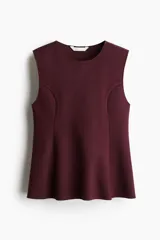 Musculosa sin mangas color vino tinto, con cuello redondo y corte peplum que se ajusta en el torso y se abre ligeramente en el ruedo. Presenta paneles laterales curvos que moldean la figura.