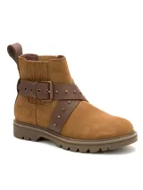 Bota de caña corta marca Caterpillar, confeccionada en gamuza color marrón. Presenta un diseño robusto con suela dentada, detalle de tiras cruzadas en cuero con tachas metálicas y hebilla ajustable lateral.