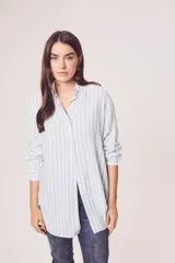 Camisa oversize celeste y blanca a rayas verticales, de mangas largas con puños abotonados y cuello camisero.