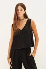 Top negro de poliéster con escote en V, tirantes con detalle de encaje y corte holgado.