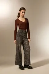 Pantalon de jean estilo baggy con estampado floral en tonos gris oscuro y blanco. Presenta un corte de pierna ancha, tiro medio y cierre frontal con botón y cremallera.