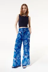 Pantalón fluido de corte flare con pretina elástica, estampado con flores, estrellas y otros motivos en tonos azules.