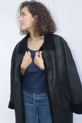 Campera tipo gamulán de cuero genuino en color marrón, con interior y detalles en corderito sintético color crema. Presenta cierre frontal con botones, cuello solapa y puños con vuelta.
