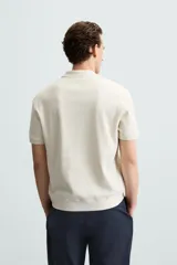 Polo de manga corta color verde oliva, con cuello solapa y abertura frontal tipo polo. Presenta una textura acanalada vertical y un calce regular.