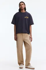 Remera negra de algodón con corte boxy y oversized, cuello redondo y mangas cortas. Cuenta con un pequeño estampado dorado en el pecho con texto y estrellas.