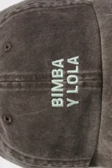 Gorro tipo gorra con visera de color marrón con efecto desgastado, con bordado frontal del logo de la marca en color verde claro.