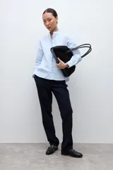 Camisa de manga larga a rayas celestes y blancas, con cuello mao y volados verticales en el frente.