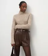 Short de poliuretano color negro, de corte recto con pinzas frontales y largo corto. Incluye un cinturón fino con hebilla y pasantes metálicos.