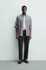 Pantalón de vestir regular fit color negro, confeccionado en tejido con mezcla de lana y elasticidad. Cuenta con cintura elástica, bolsillos frontales, bolsillos traseros de vivo con botón, y cierre frontal con cremallera y botón.