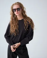 Buzo negro de punto tramado italiano con mangas voluminosas, escote redondo y detalles de bordado en sisas y recortes de manga.