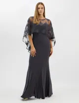 Vestido largo de corte sirena en color azul oscuro, confeccionado en tejido de punto con caída fluida. Presenta una capa integrada de tul fino sobre los hombros y el pecho, decorada con bordados florales a tono y lentejuelas brillantes. Posee escote redondo y cierre invisible en la espalda.