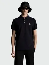 Polo de piqué de algodón color negro, con cuello clásico, tapeta de botones y logo de la marca bordado en el pecho.