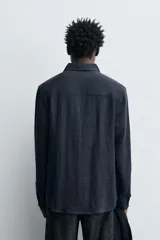 Camisa de corte relajado confeccionada en tejido fluido con mezcla de viscosa. Presenta cuello solapa, cierre frontal con botones y manga larga con puños abotonados.