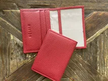 Tarjetero rojo de cuero vacuno con ranuras para tarjetas y bolsillo exterior en el dorso.