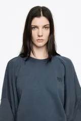 Buzo de algodón color negro con efecto gastado, corte globo y mangas largas ranglán. Presenta un logo bordado discreto en el pecho.