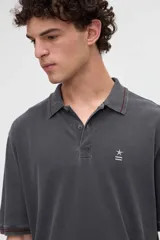 Remera polo manga corta color blanco, confeccionada en tela piqué de algodón lavado con textura extra suave. Cuenta con media cartera de botones, cuello y puños acanalados con diseño de líneas a contratono, y bordado sutil de la marca en el pecho. Calce clásico.