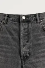Jeans de denim de algodón color gris con efecto lavado, de corte relaxed barrel fit y tiro medio. Presenta diseño amplio con pinzas en las rodillas y costuras curvas, cierre frontal con botones y cinco bolsillos tradicionales.
