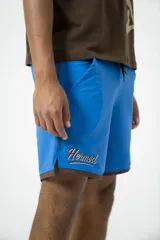 Short deportivo azul con ribete marrón y logo bordado en el muslo.