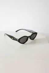 Lentes de sol con silueta geométrica y angular de estilo cat-eye hexagonal, armazón negro y cristales oscuros con protección UV400.